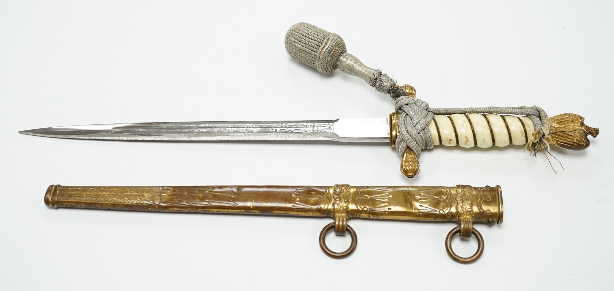 A WWII German naval officer's dagger, by Eickhorn, etched blade, roughly sharpened on one edge, regulation brass mounts, composition grip, silver bullion dress knot. Condition - fair, worn with locking catch removed